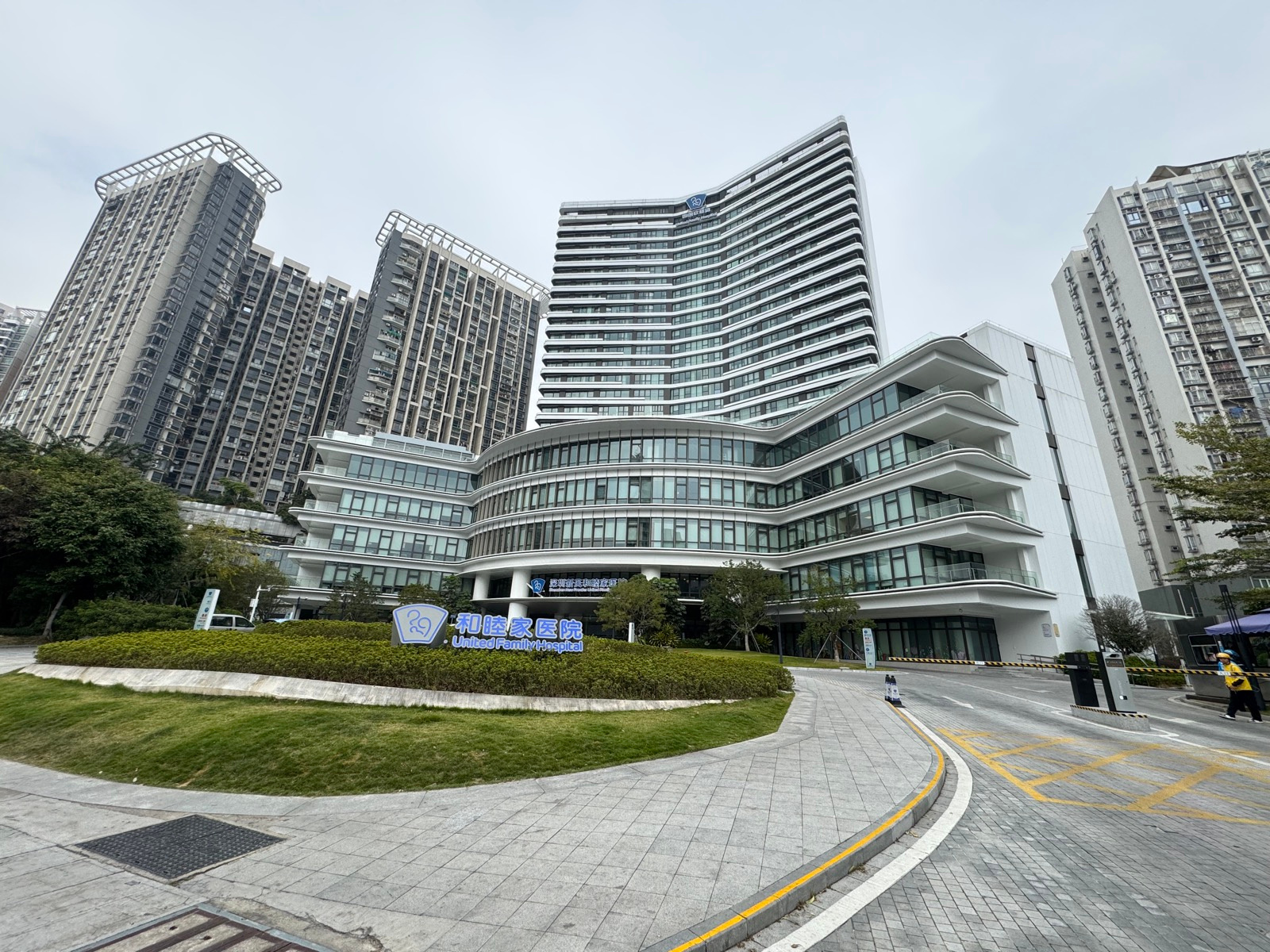 Modern curved white building of a private United Family hospital in Shenzhen with bilingual sign